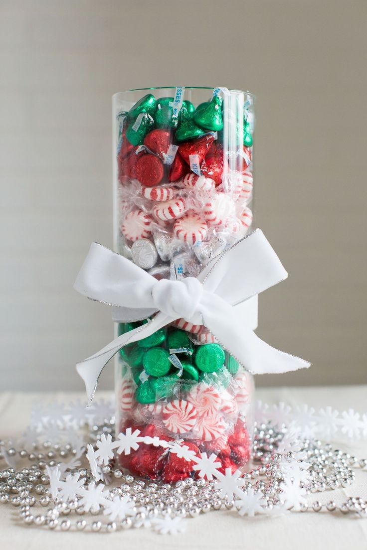 a glass jar filled with candy canes and candies on top of snow flakes