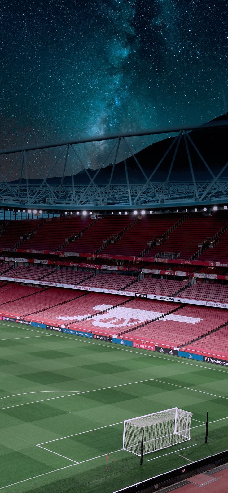 an empty soccer field with the stars in the sky above it and some lights on