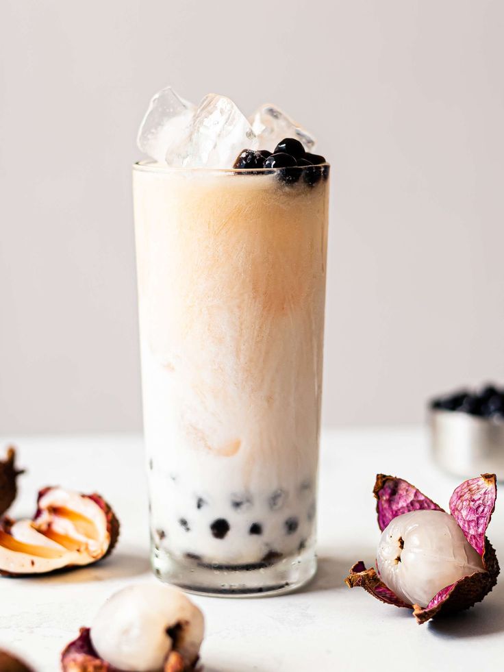 an iced drink with blueberries and ice sits on a table next to some fruit