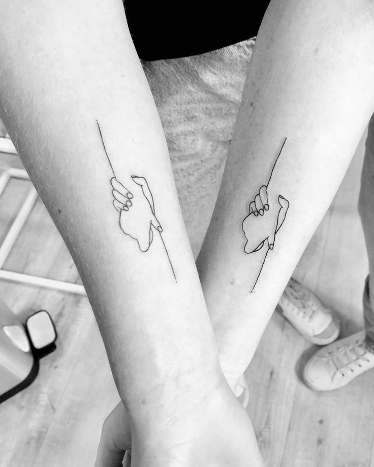 two people with matching tattoos on their arms, one is holding the other's hand