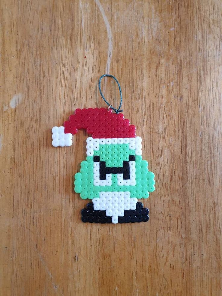 a christmas ornament made out of perler beads on a wooden table top