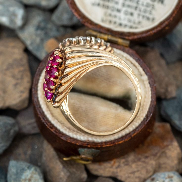 This retro-vintage circa 1950s by-pass ring features a fluted design. The ring is accented with a cluster of ten (10), prong set, round brilliant cut diamonds and ten (10), prong set, round mixed cut natural rubies. The ring measures 20.8mm at the top, rises 8.8mm above the finger, tapering to 3.2mm wide and 1.1mm thick at the base of the shank. It is currently a size 5. One of the diamonds has a small, unnoticeable chip. Vintage Multi-stone Diamond Rings, Vintage Multi-stone Diamond Ring Collectible, Vintage 14k Gold Cluster Jewelry, Vintage Multi-stone Diamond Ring For Collectors, Vintage Cluster Ring In 14k Gold, Vintage Multi-stone Diamond Ring In Yellow Gold, Vintage Brilliant Cut Cluster Ruby Ring, Vintage Ruby Ring With Brilliant Cut Cluster, Vintage Cluster Ruby Ring With Brilliant Cut