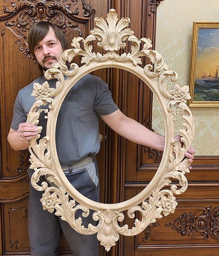 a man is holding up a large mirror