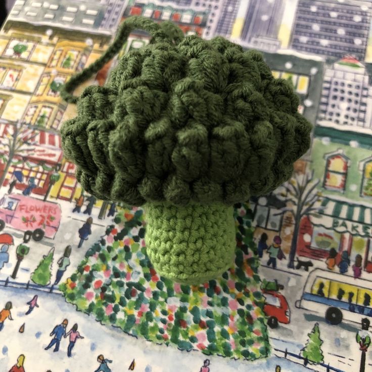 a crocheted broccoli head sitting on top of a colorful table cloth