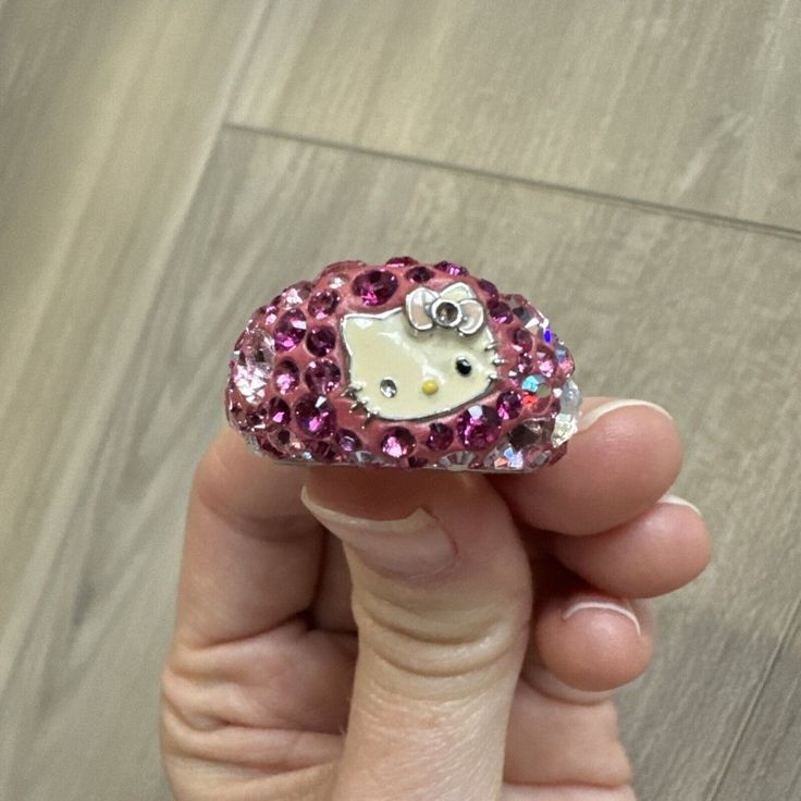 someone is holding a hello kitty brooch in their hand