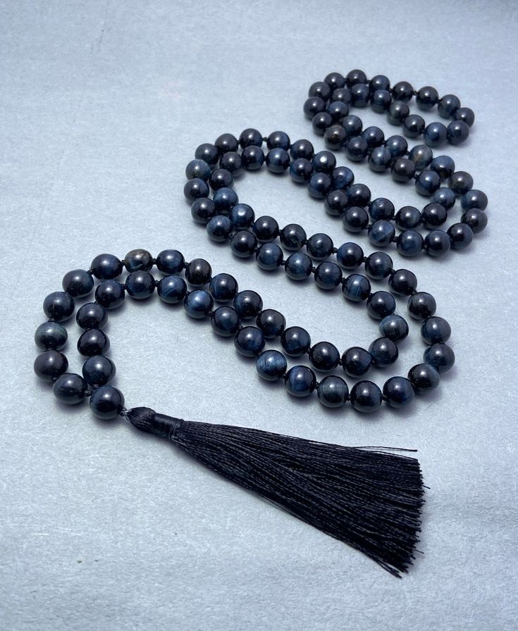 This traditional mala is hand-knotted with Hawk's Eye beads chosen specifically for their connection to the heart chakra. This stunning necklace is a gorgeous and useful statement piece and the perfect gift for anyone needing peace during an emotional time. Meditation can be an integral part of healing from loss and trauma as the repetition of a healthy mantra can help ease the feelings of anxiety often felt during an emotional time. Hawk's Eye Healing Powers : Strength | Aventurine for Manifest Hawk Eye, Manifesting Wealth, Eye Beads, Stunning Necklace, Healing Powers, Eye Shapes, Inner Strength, Heart Chakra, Chain Styles