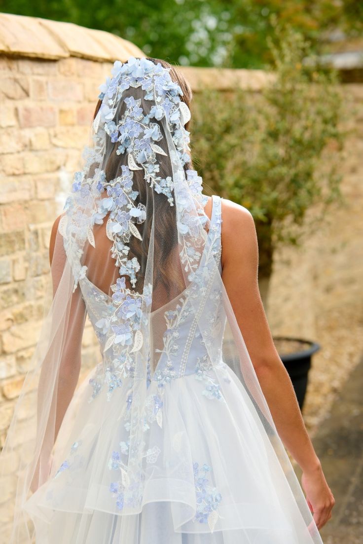 the back of a bride's wedding dress, with flowers on it and veil over her head