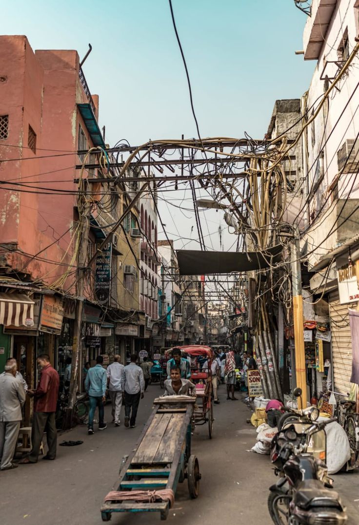 people are walking down an alley way with many wires above them and on the ground