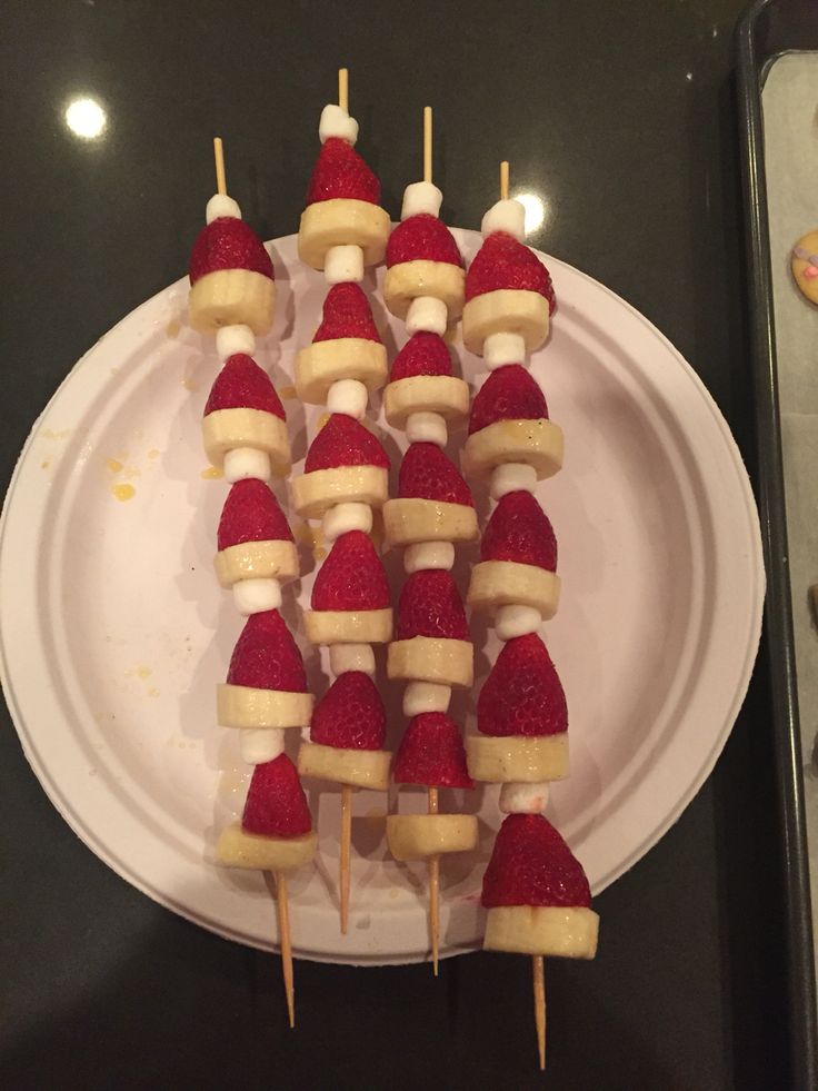 strawberries and bananas are arranged on skewers with banana slices in the shape of santa's hats