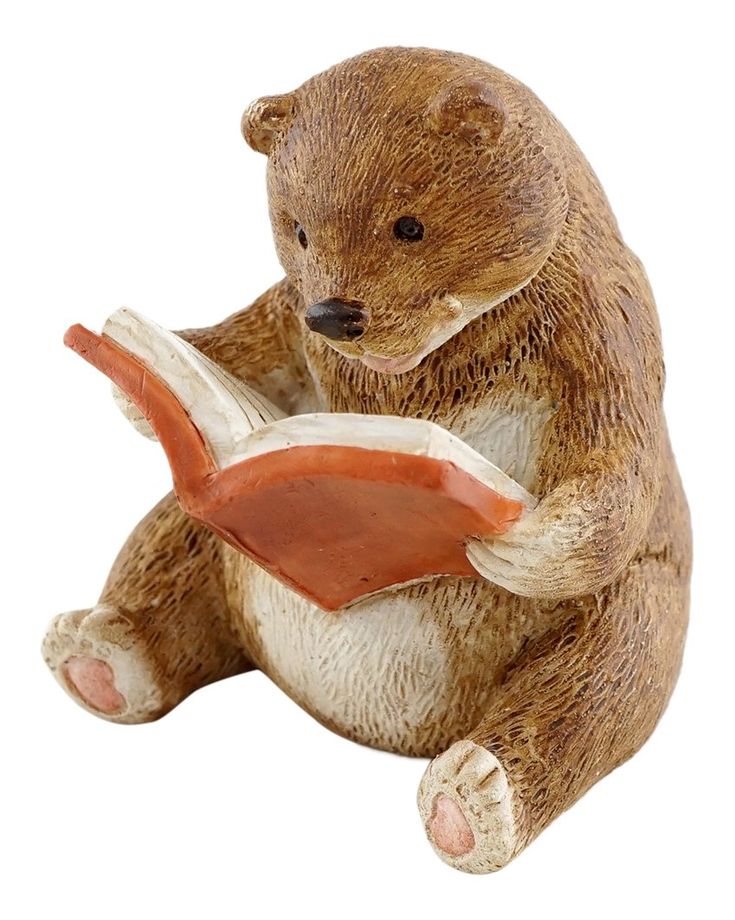 a ceramic bear reading a book with its paws on it's knees and legs