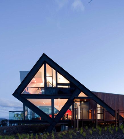 an unusual house is lit up at night with the lights on and windows open to let in natural light