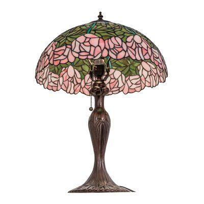 a table lamp with pink flowers on the shade and chain hanging from it's base