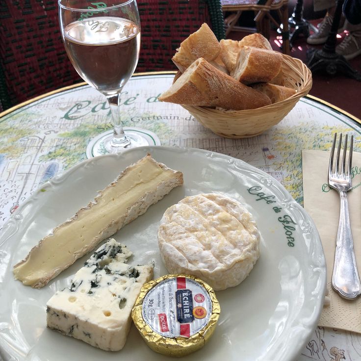 cheese and crackers on a plate with a glass of wine