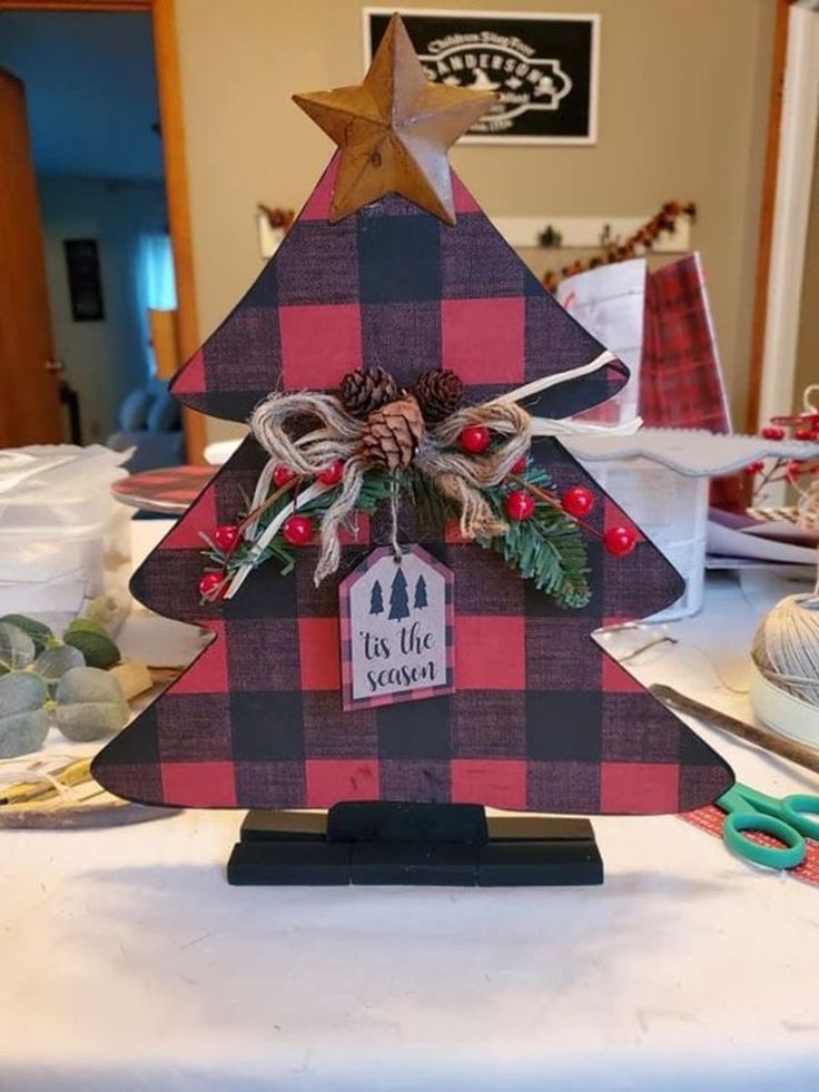 a christmas tree made out of plaid paper with scissors on the table next to it