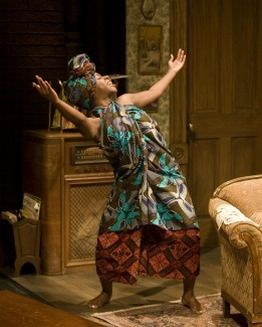 a woman standing in front of a couch with her hands up to the ceiling and arms wide open