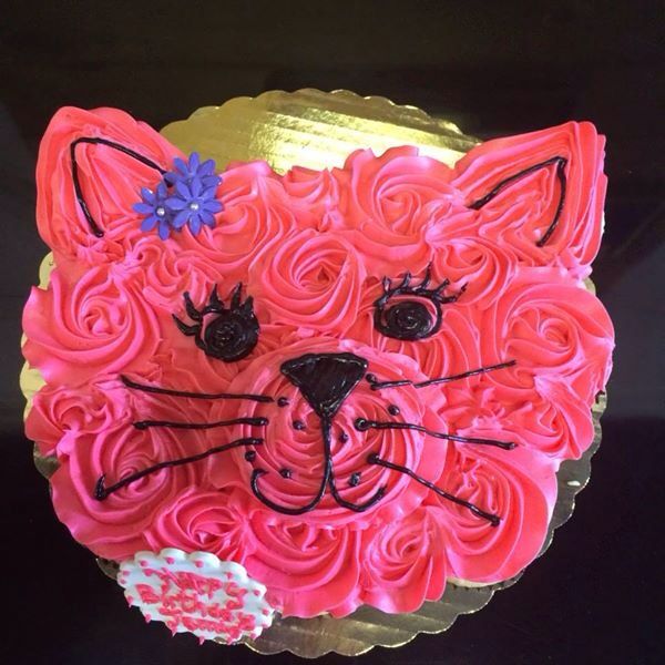 a cake shaped like a cat with pink frosting and flowers on it's head