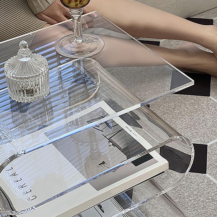 a person sitting at a glass table with a wine glass on it and a book in front of them