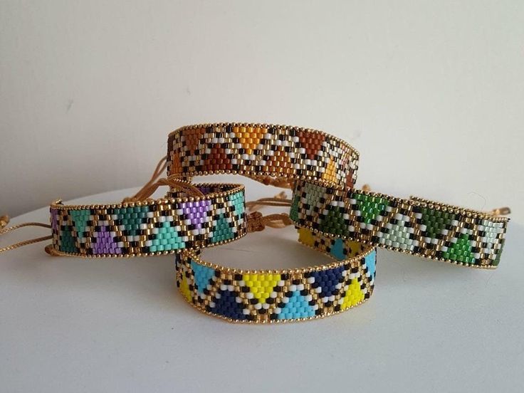 four bracelets with multicolored beads on white surface next to eachother