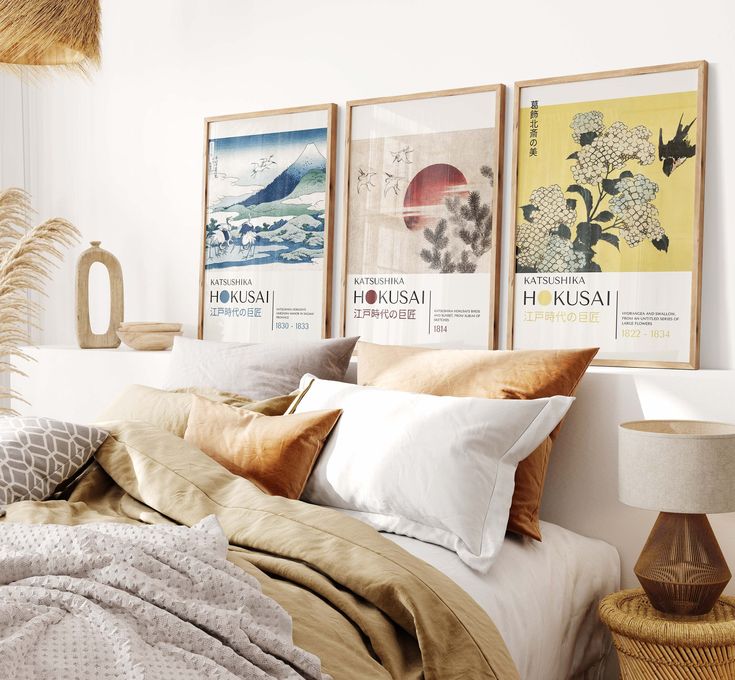 a bed with pillows and blankets on top of it next to two pictures hanging on the wall