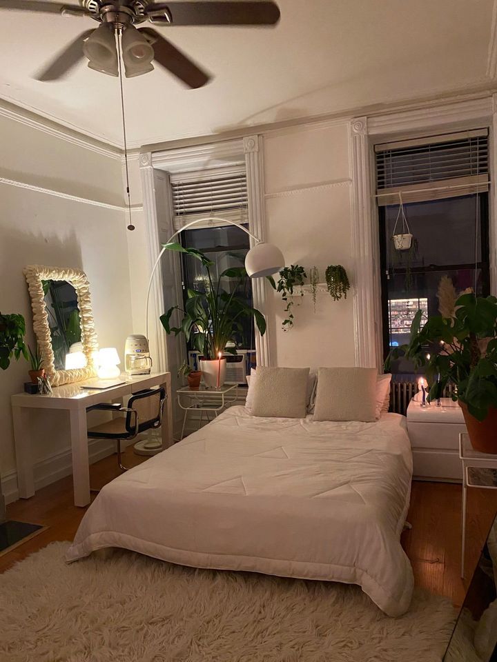 a bedroom with a white bed and lots of plants