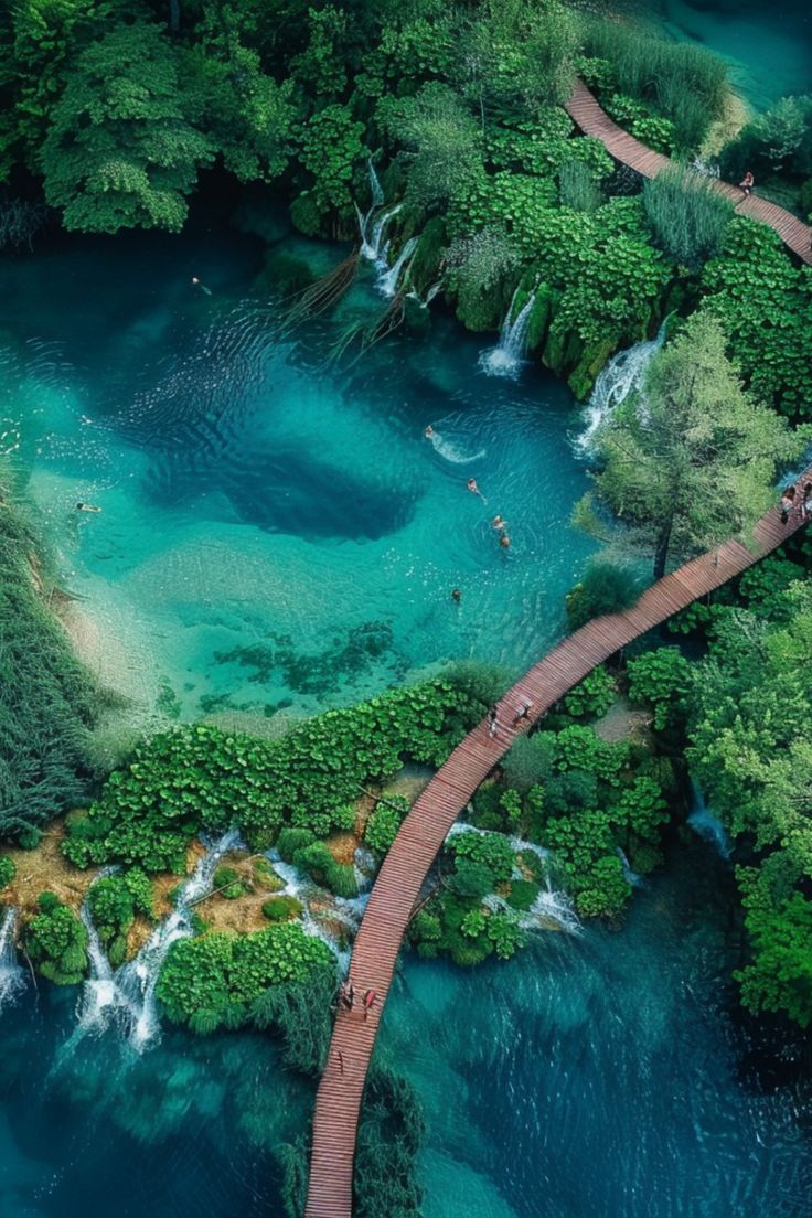 an aerial view of people walking on a wooden walkway over blue water