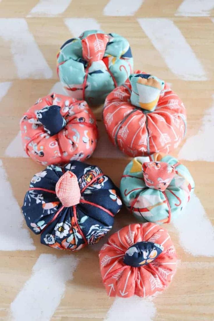 several small pumpkins are sitting on the floor next to each other and one is wrapped in fabric