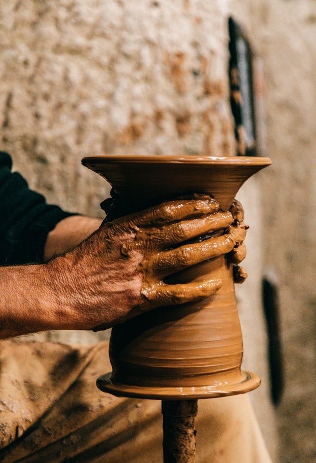 a man is making a vase out of clay with his hands on the potter's wheel