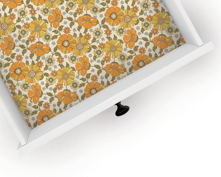 an orange and yellow flowered wallpaper in a white frame with black knobs