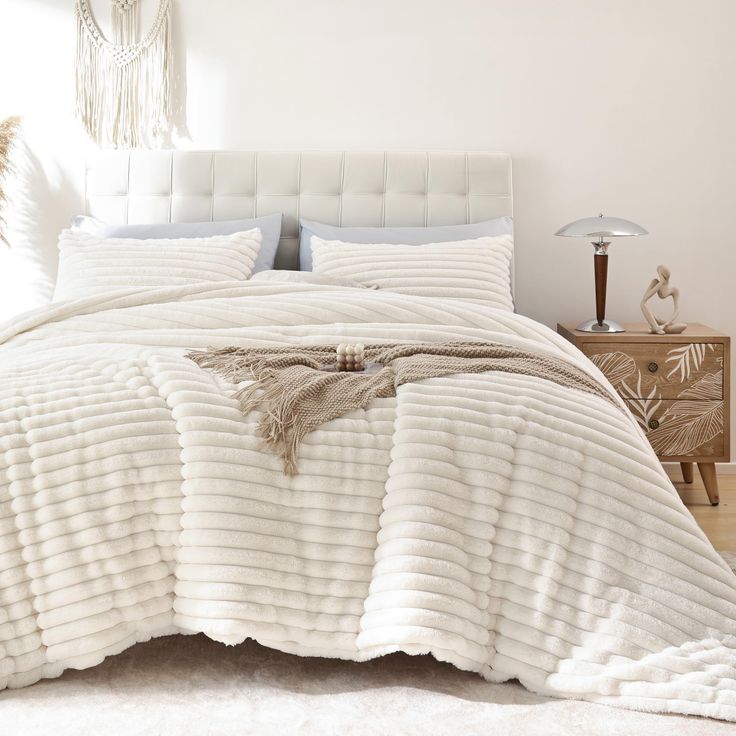 a bed with white comforter and pillows in a room