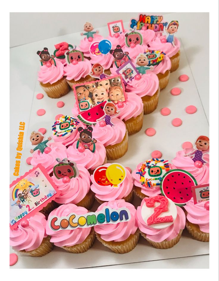 cupcakes with pink frosting and decorations are arranged on a table