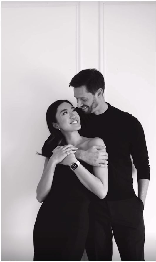 two people standing next to each other in front of a white wall and one person is hugging