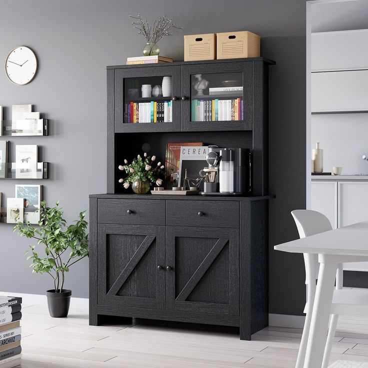 a black bookcase with doors and drawers in a living room next to a white table