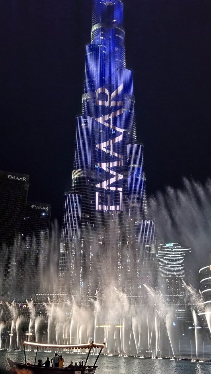 there is a boat that is in front of the burj building and water fountain