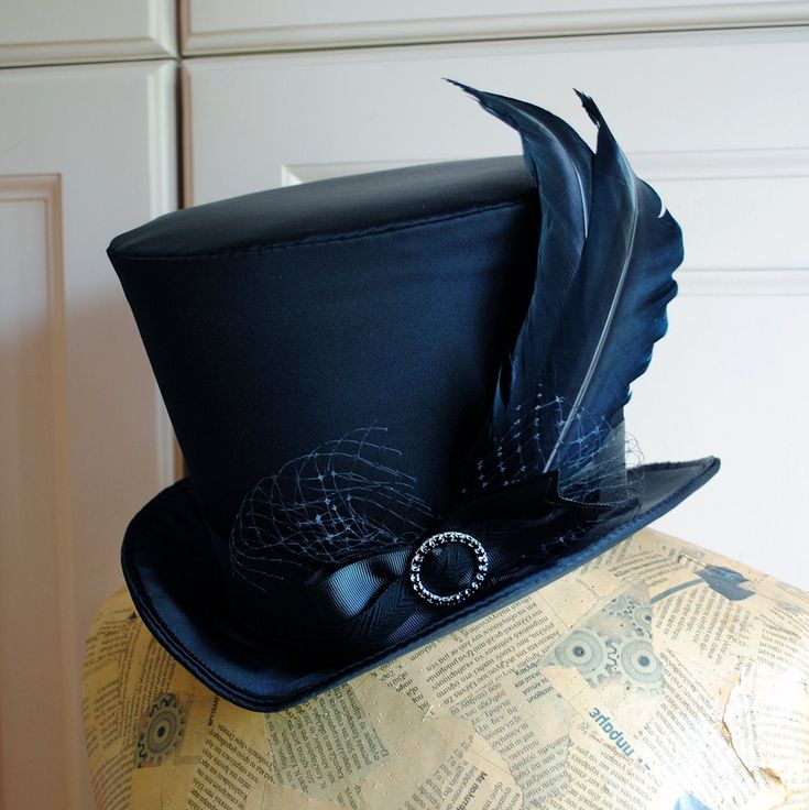 The Liza is a striking cabaret inspired full size top hat. It is covered with beautiful shiny black satin. It is decorated with black ribbon around the crown, black veil, half bow with black crystal buckle and two elegant black goose feathers. Also available as a medium size mini top hat: https://www.etsy.com/listing/256101614/victorian-witch-hatblack-mini-top?ref=shop_home_active_14 Need this TOP HAT in another color?Just send me a message to talk about a custom hat made just for you! This hat Gothic High Crown Costume Hat, Gothic High Crown Halloween Hat, Gothic Fitted High Crown Costume Accessories, Gothic Short-brim Hat For Costume Party, Gothic Fitted Hat With Short Brim, Gothic Top Hat With Short Brim For Halloween, High Crown Top Hat For Halloween, Steampunk Top Hat With Curved Brim For Costume, Vintage Top Hat With Curved Brim For Costume Party