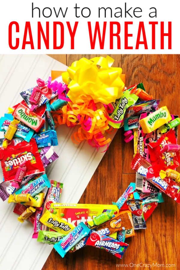 a wreath made out of candy bars on top of a wooden table next to a white piece of paper