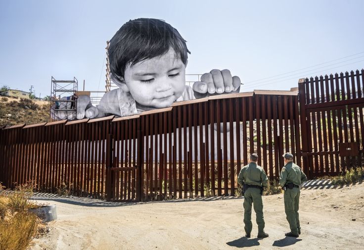 two men standing in front of a wall with an image of a baby on it