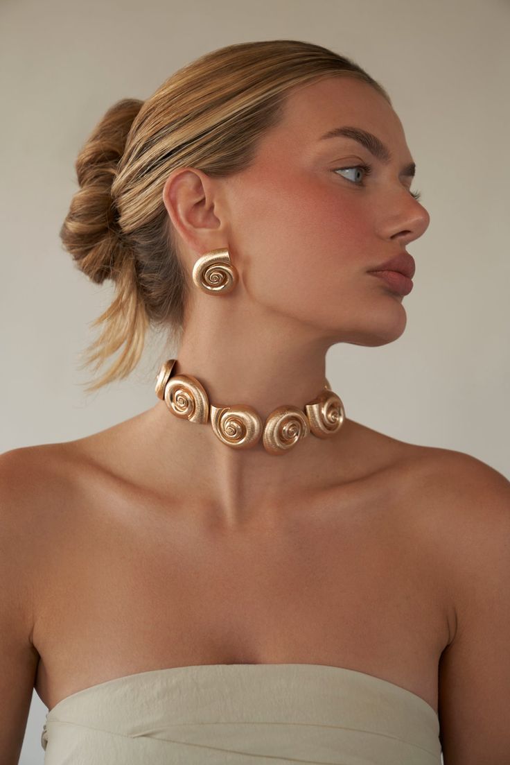 Final Sale cannot be returned or exchanged. Metal nautilus shell choker 14kt Gold plated brass or Rhodium plated brass Charms measures approx. 36mm each Necklace measures 12" with a 3" extender Hook Closure Product Care: METAL: Use a soft cloth to gently wipe clean, then remove any remaining impurities with mild diluted soap. Rinse with warm water and dry thoroughly before storing in the provided jewelry pouch. Do not use abrasive cleaners, steamers or ultrasonic machines. GEMSTONE: Avoid contac Luxury Bohemian Shell Accessories, Luxury Round Ocean-inspired Jewelry, Gold Plated Spiral Jewelry, Adjustable Spiral Gold Jewelry, Adjustable Gold Spiral Necklace, Adjustable Spiral Gold Necklace, Jewellery Photography Inspiration, Bold Statement Jewelry, Shell Choker