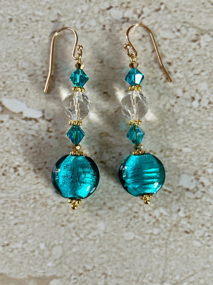 Venetian Glass Earrings featuring a 14MM teal round Venetian foil bead accented with Blue Zircon A/B Swarovski crystals and an 8MM  faceted crystal beads and a gold plated bead cap. Gold Filled Earwires. Handmade GIFT BOXED Elegant Round Glass Earrings, Elegant Glass Crystal Drop Earrings, Elegant Nickel Free Glass Earrings, Elegant Nickel-free Glass Earrings, Elegant Turquoise Glass Jewelry, Blue Round Glass Earrings, Round Glass Earrings For Parties, Elegant Crystal Glass Earrings For Gifts, Elegant Glass Crystal Earrings For Gift