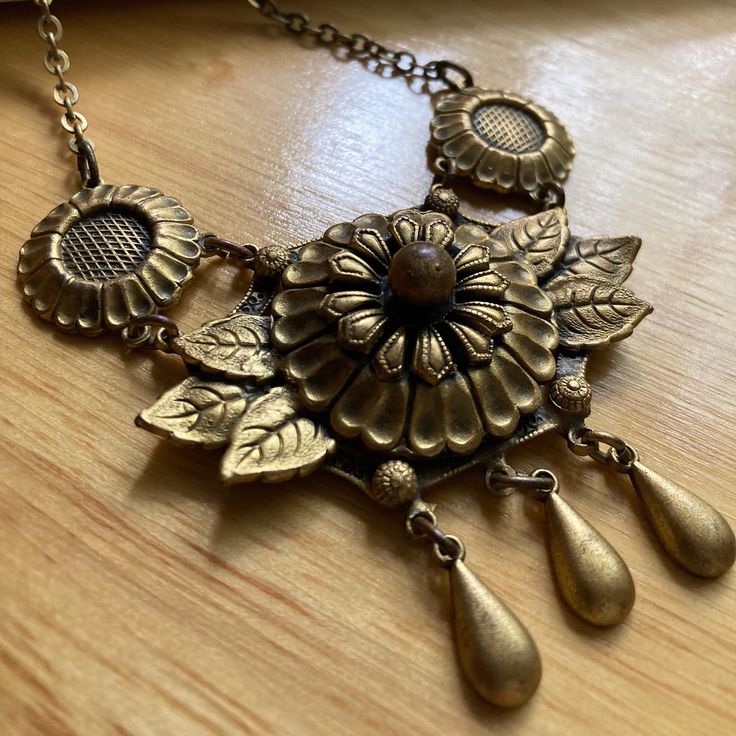 This unique Arts & Crafts style choker, created sometime in the 1930's features layered brass pieces in a floral and leaf motif.  This fabulous necklace is in amazing condition for its age and the unusual design makes it a standout piece in any jewelry collection. The central piece is 2" wide by 2.5" long and it measures 18" end to end.  Spring ring closure is secure and works well. Free shipping always! Everything I offer in my shop is in good wearable condition. Please consider that vintage je Vintage Festival Necklace With Vintage Charm, Vintage Necklace With Vintage Charm For Festivals, Vintage Necklaces With Vintage Charm For Festival, Gold Vintage Charm Necklace For Festival, Gold Necklace With Vintage Charm For Festival, Vintage Metal Jewelry For Festivals, Vintage Antique Gold Necklaces For Festival, Vintage Antique Gold Necklace For Festival, Bohemian Patina Necklaces Collectible