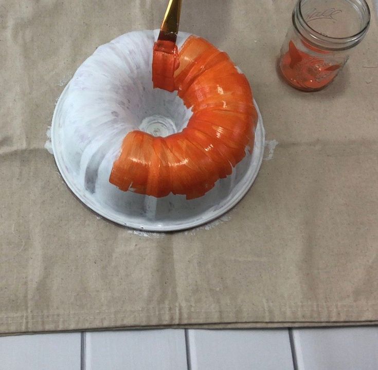 an orange piece of cake sitting on top of a white plate next to a jar