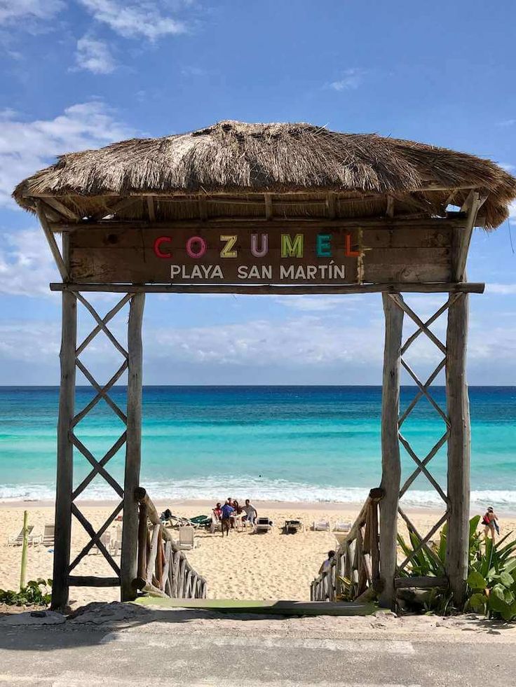 a wooden gazebo sitting on top of a sandy beach next to the blue ocean