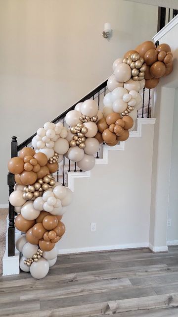 the balloon staircase is decorated with gold, white and brown balloons that are hanging from the banister