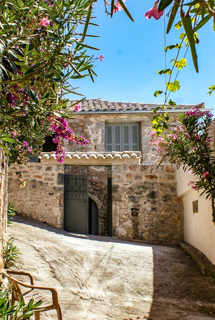 an old stone house with pink flowers on the outside