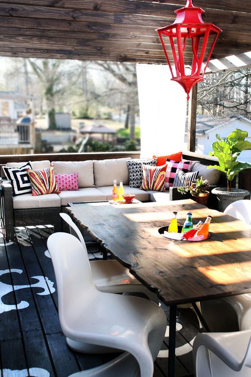 an outdoor dining area with white chairs and wooden table