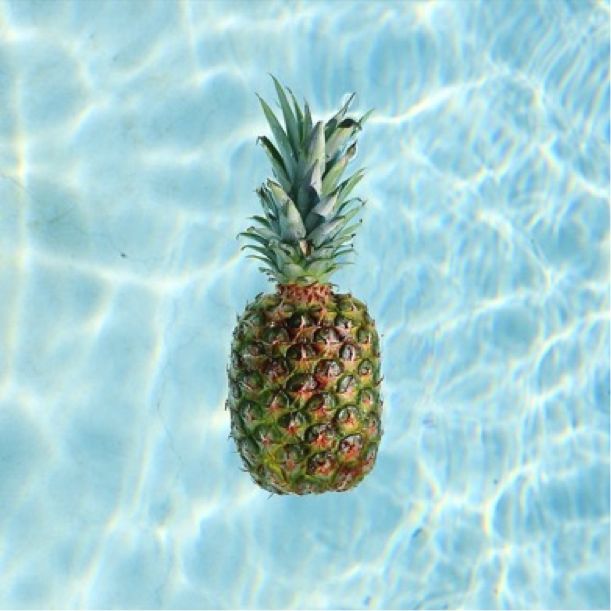 a pineapple floating on top of a blue swimming pool with water ripples around it