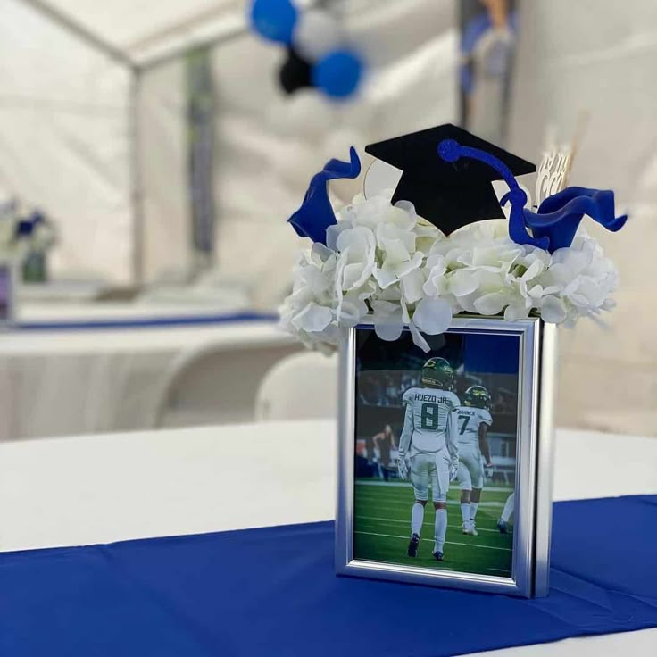 a blue and white graduation decoration with flowers in a vase on top of a table