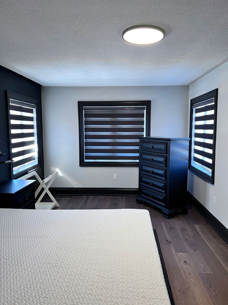 a bedroom with black shutters and white bedding