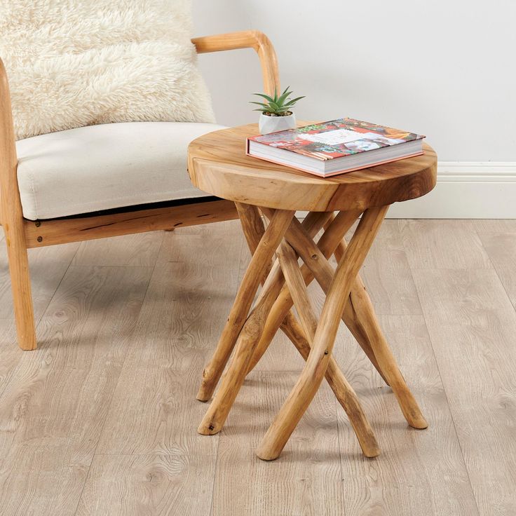 a small wooden table with a magazine on it next to a white chair and pillow