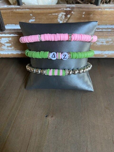 three different bracelets sitting on top of a pillow in front of a wooden bench