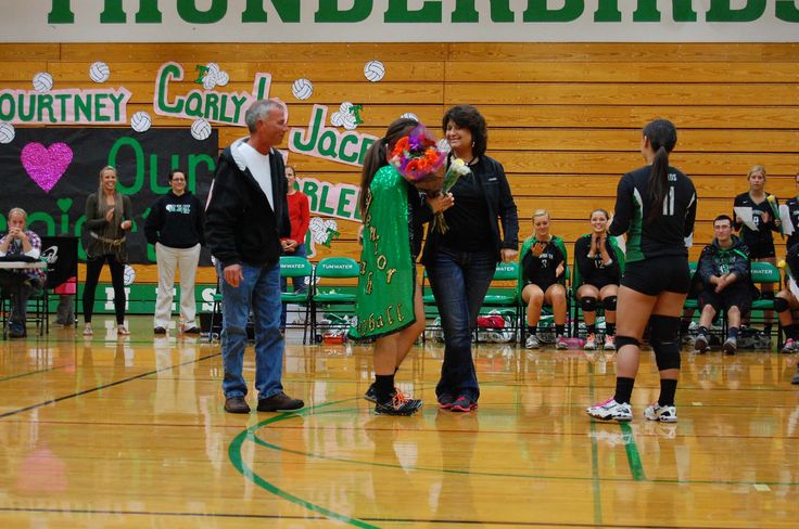 some people are standing on a basketball court and one person is holding flowers in her hand